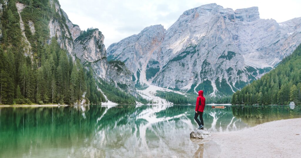 a person standing on a rock in a lake with mountains in the background