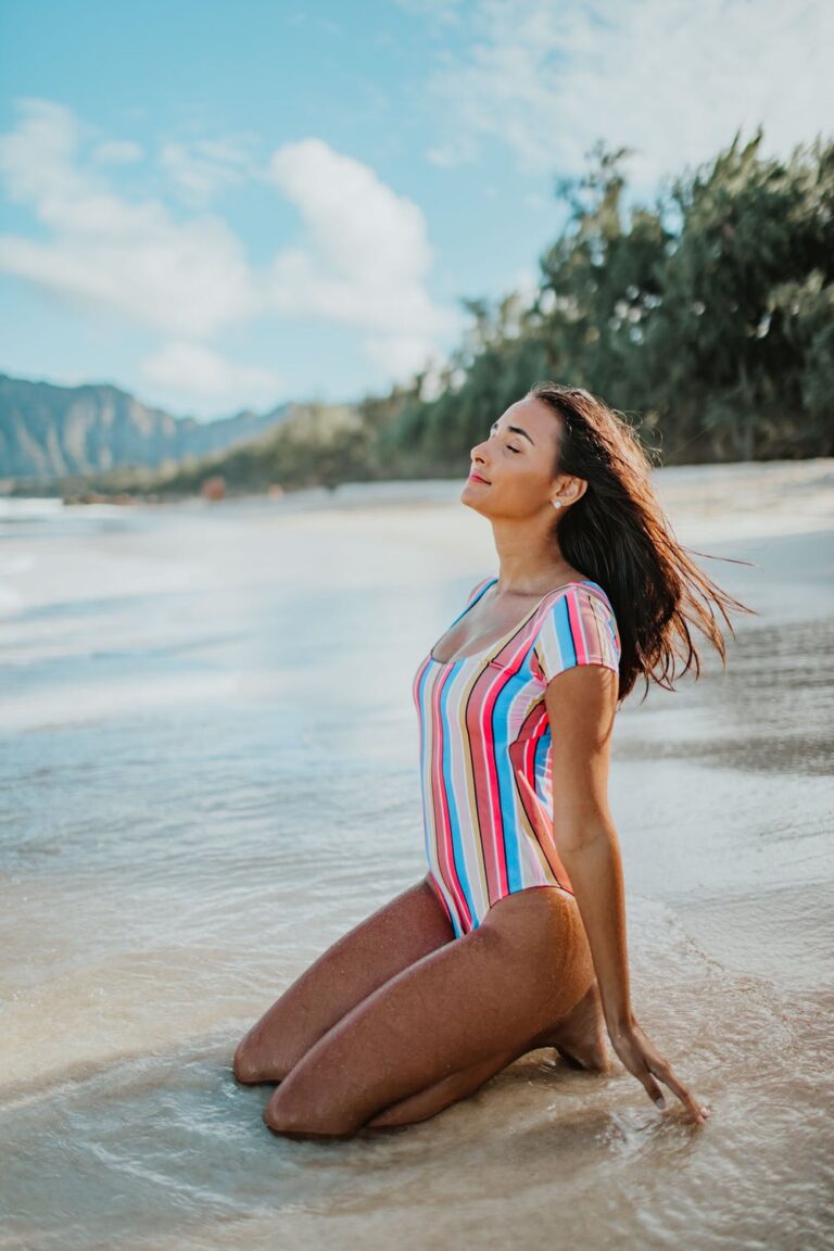 a woman in a colorful dress sitting on a beach